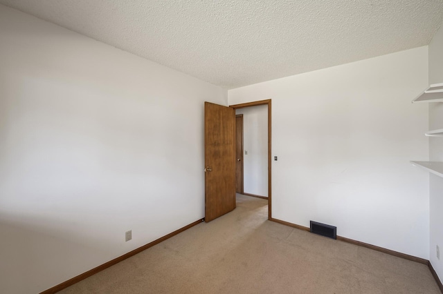 empty room with a textured ceiling and light carpet