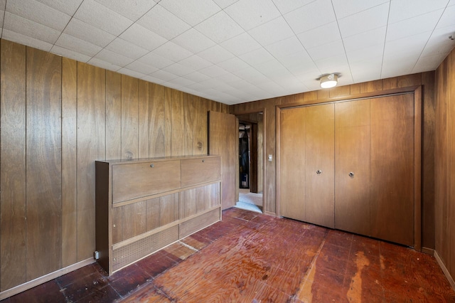 unfurnished bedroom with wood walls and a closet