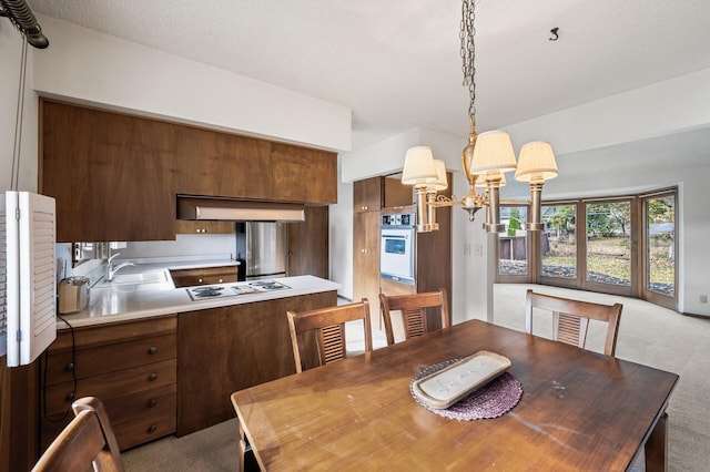 dining space with light colored carpet, a textured ceiling, sink, and an inviting chandelier