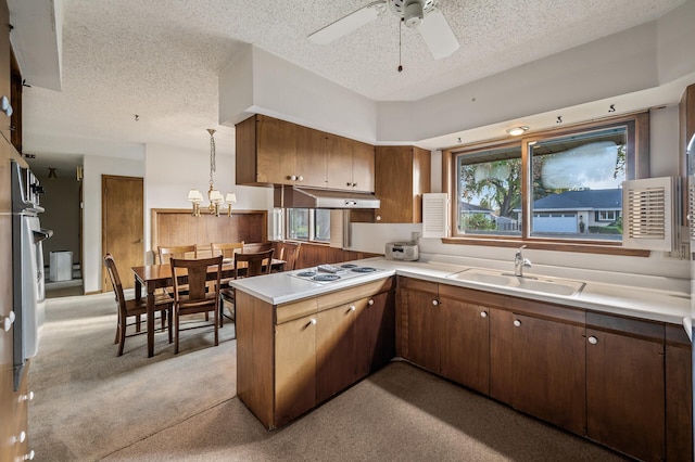 kitchen with a textured ceiling, kitchen peninsula, sink, and hanging light fixtures