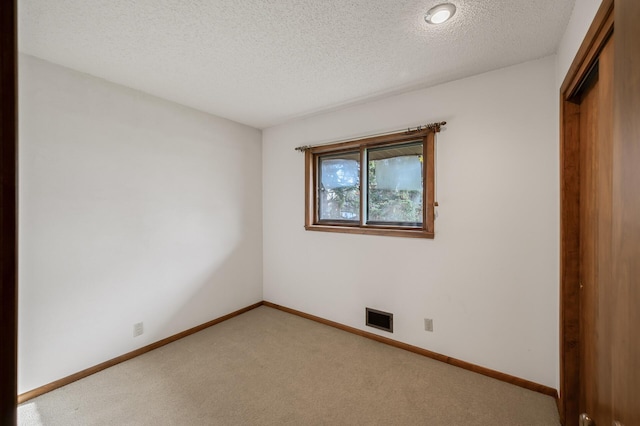 carpeted empty room featuring a textured ceiling