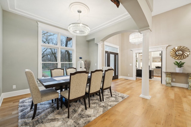 dining area with a chandelier, light hardwood / wood-style flooring, and decorative columns