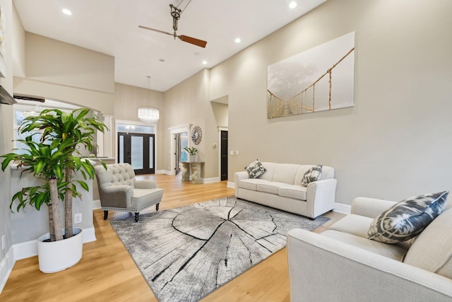 living room with french doors, a towering ceiling, ceiling fan, and light wood-type flooring