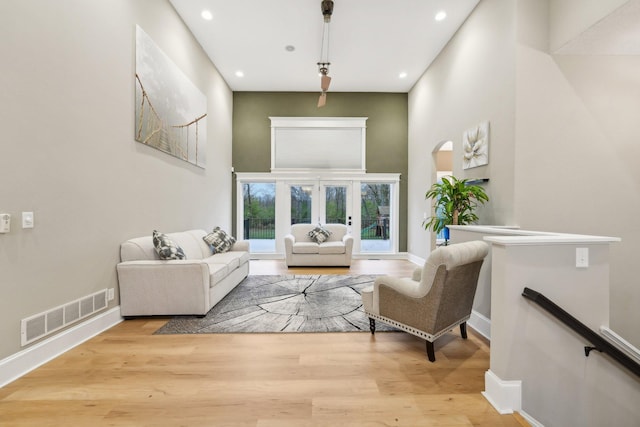 living room featuring a towering ceiling and light hardwood / wood-style flooring