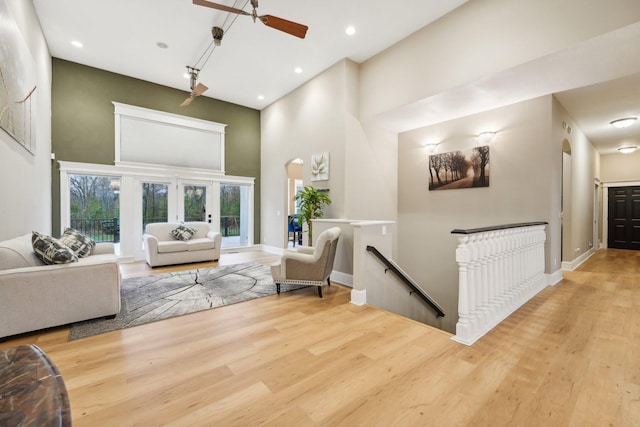 living room featuring a towering ceiling, light hardwood / wood-style floors, and ceiling fan