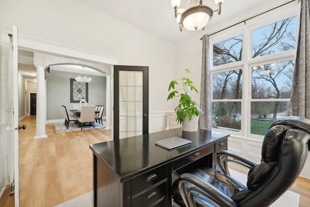 office space featuring an inviting chandelier, ornate columns, light wood-type flooring, and crown molding