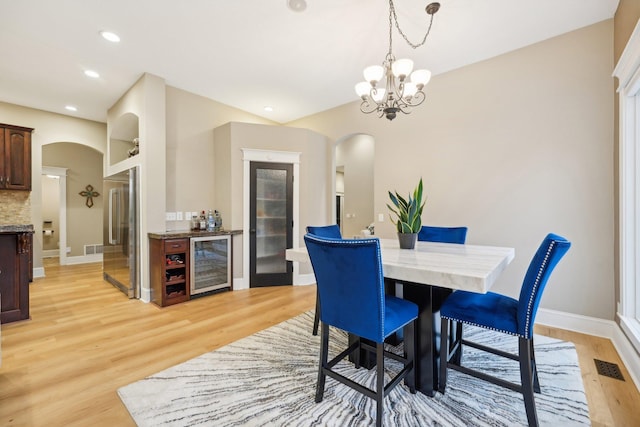 dining area featuring wine cooler, light wood-type flooring, and bar area