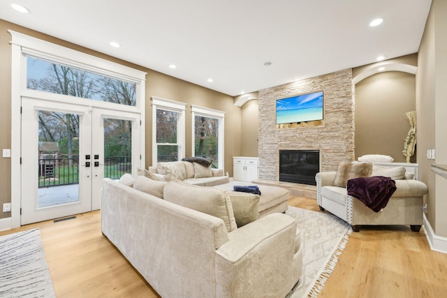 living room with a fireplace, light wood-type flooring, and french doors