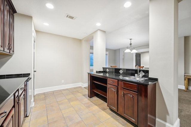 kitchen featuring dark brown cabinets, sink, and decorative light fixtures