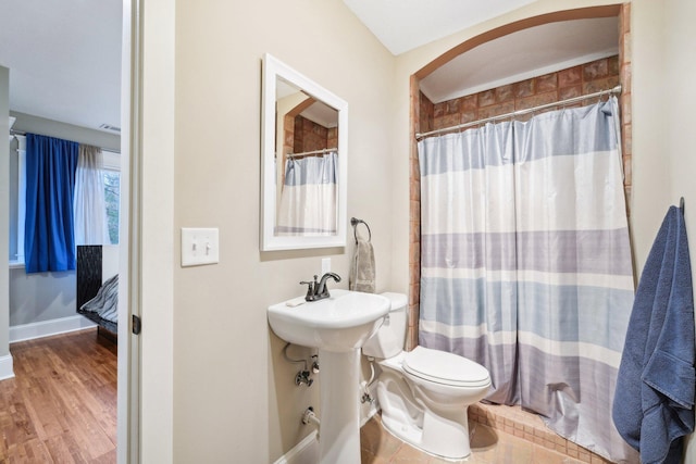 bathroom featuring toilet, a shower with curtain, and wood-type flooring