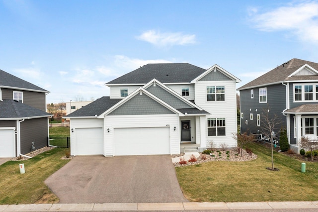 craftsman-style house featuring a garage, a front lawn, aphalt driveway, and roof with shingles