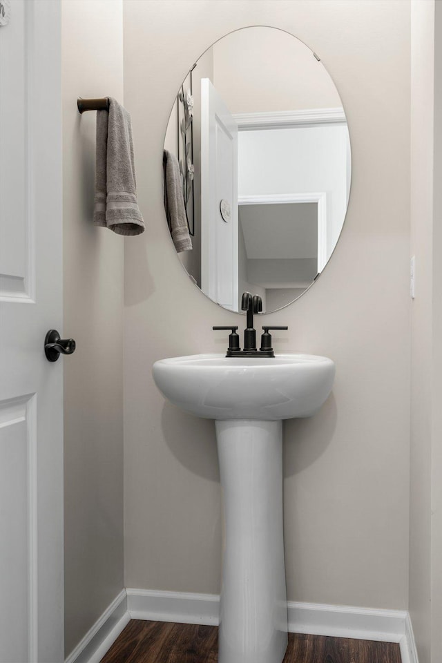 bathroom featuring baseboards, a sink, and wood finished floors