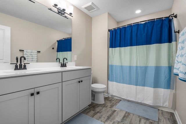 full bath with visible vents, a sink, and wood finished floors