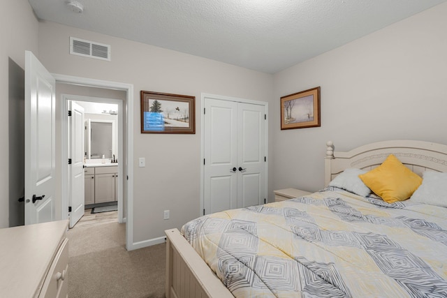bedroom with visible vents, a closet, light carpet, baseboards, and a sink