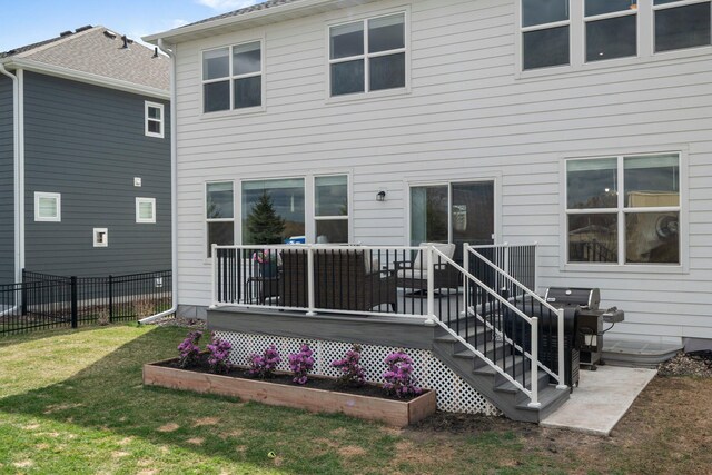 back of property featuring fence, a wooden deck, and a lawn