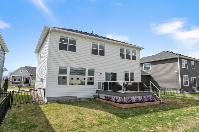 back of property with a fenced backyard, a yard, and a deck