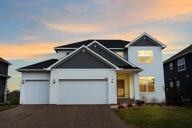 traditional home with a garage, a front lawn, aphalt driveway, and fence