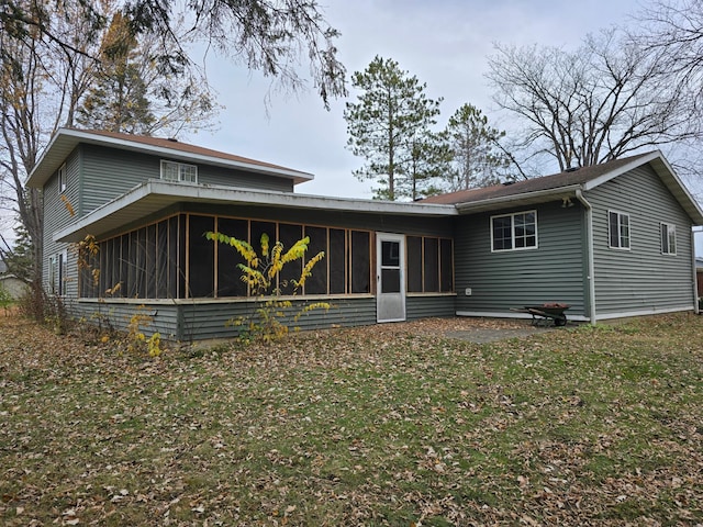 rear view of house with a lawn and a sunroom