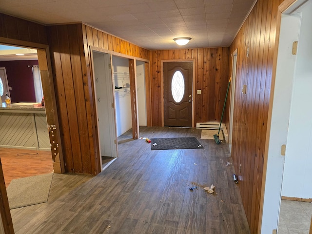 entryway featuring a baseboard heating unit, wooden walls, and wood finished floors