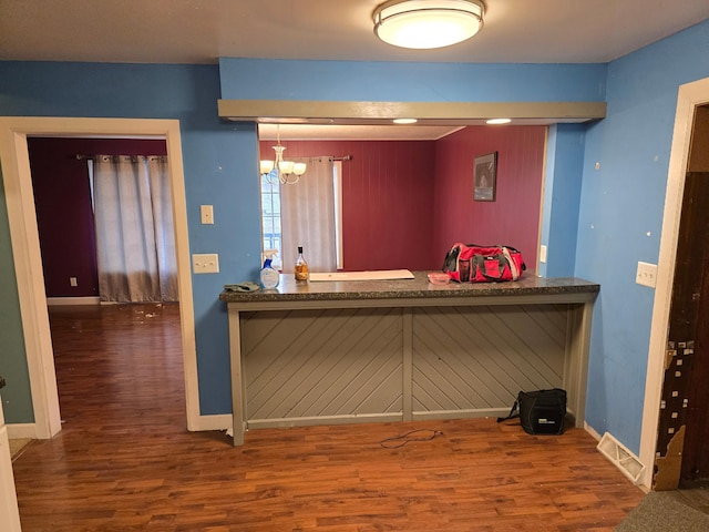 bar featuring a chandelier, baseboards, visible vents, and wood finished floors