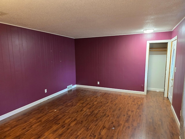 unfurnished room with wood walls, hardwood / wood-style floors, crown molding, and a textured ceiling