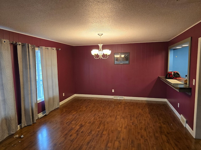 unfurnished room featuring a notable chandelier, visible vents, a textured ceiling, and wood finished floors