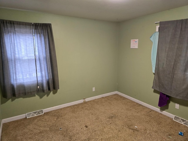 carpeted empty room featuring baseboards and visible vents