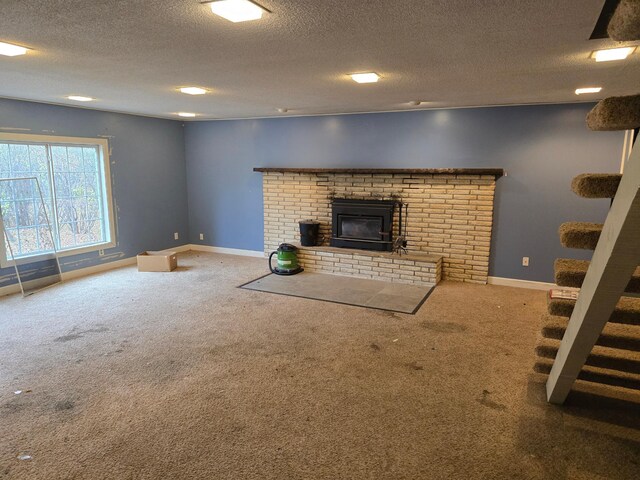 unfurnished living room with a brick fireplace, carpet floors, a textured ceiling, baseboards, and stairs