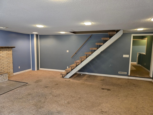 finished below grade area featuring a textured ceiling, baseboards, carpet floors, and stairs