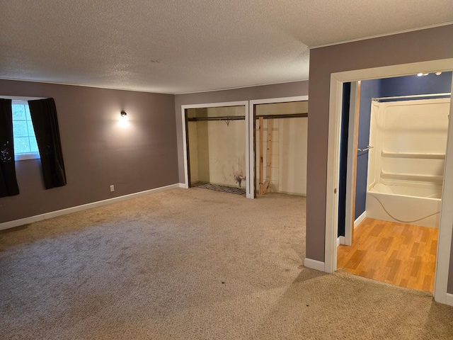 unfurnished bedroom with multiple closets, a textured ceiling, and carpet floors