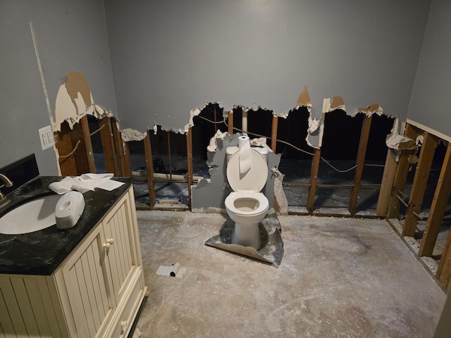 bathroom with vanity, toilet, and concrete floors