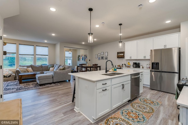 kitchen with an island with sink, appliances with stainless steel finishes, light countertops, white cabinetry, and a sink