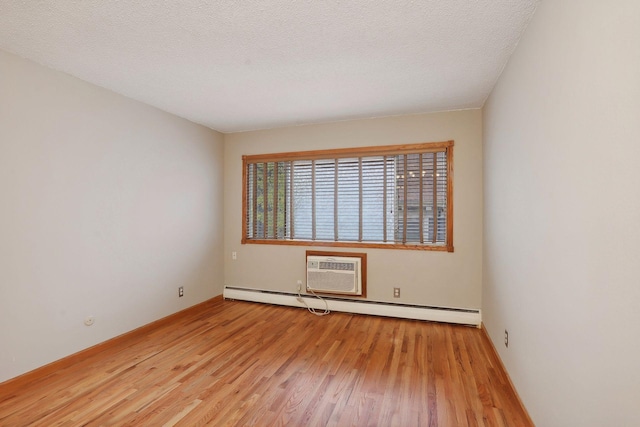 unfurnished room featuring baseboard heating, an AC wall unit, light hardwood / wood-style flooring, and a textured ceiling