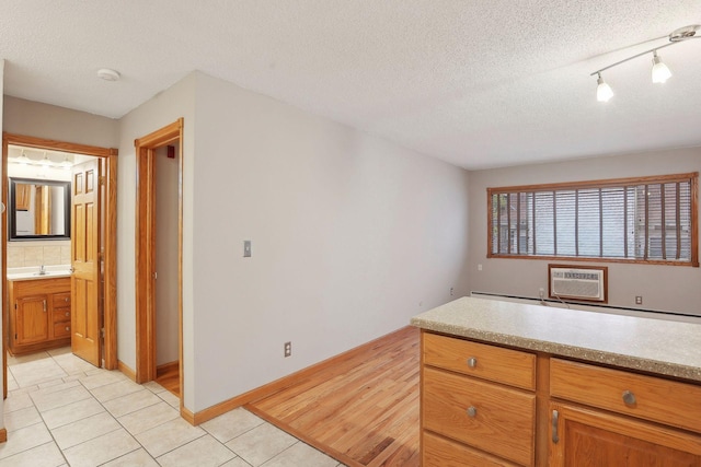 kitchen with sink, a wall mounted AC, a textured ceiling, and light tile patterned flooring