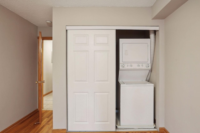 washroom with stacked washer / dryer, a textured ceiling, and light hardwood / wood-style flooring