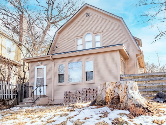 view of front of house with fence and a gambrel roof