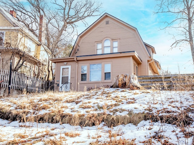 exterior space featuring fence and a gambrel roof