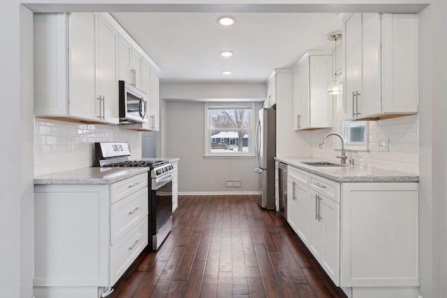 kitchen with stainless steel appliances, white cabinets, sink, and light stone counters