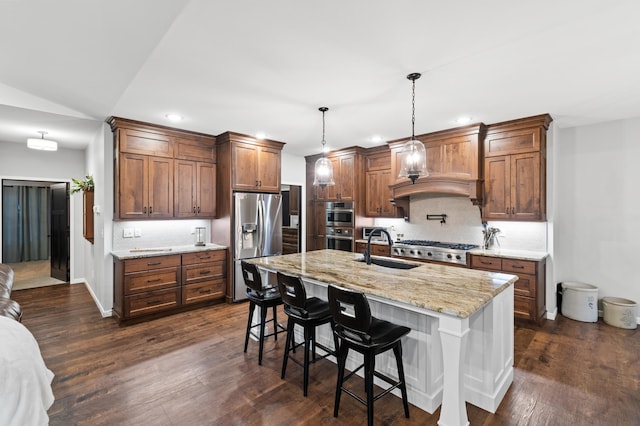 kitchen featuring pendant lighting, sink, an island with sink, appliances with stainless steel finishes, and a kitchen bar