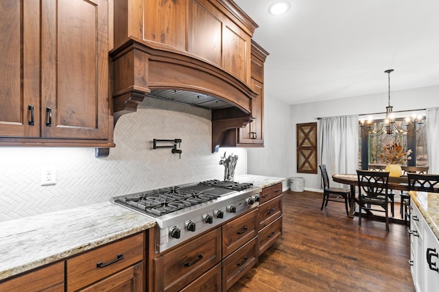 kitchen featuring decorative backsplash, light stone countertops, a notable chandelier, dark hardwood / wood-style flooring, and stainless steel gas cooktop