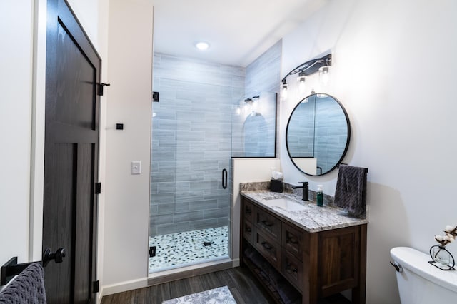 bathroom featuring toilet, vanity, an enclosed shower, and hardwood / wood-style flooring