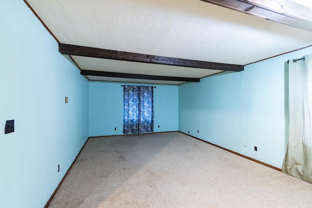 empty room with beamed ceiling, a textured ceiling, and light colored carpet