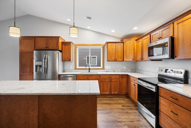 kitchen featuring stainless steel appliances, lofted ceiling, hanging light fixtures, hardwood / wood-style flooring, and sink