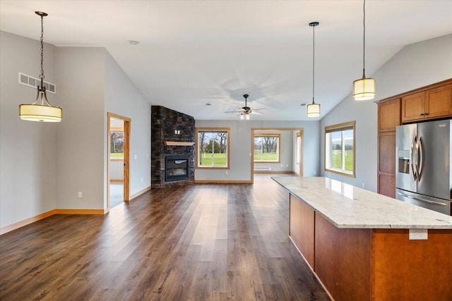 kitchen with hanging light fixtures, vaulted ceiling, stainless steel fridge, and dark hardwood / wood-style floors