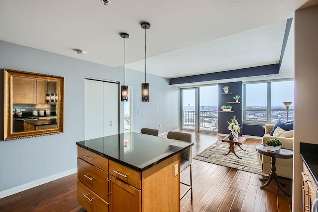 kitchen with hanging light fixtures, a kitchen island, dark hardwood / wood-style floors, and a kitchen bar