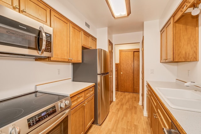 kitchen with light hardwood / wood-style floors, sink, and appliances with stainless steel finishes