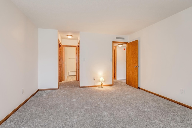 unfurnished bedroom with baseboard heating and light carpet