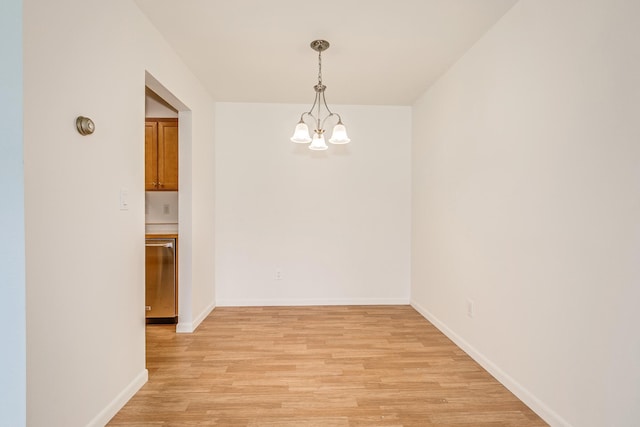 unfurnished dining area featuring an inviting chandelier and light hardwood / wood-style floors