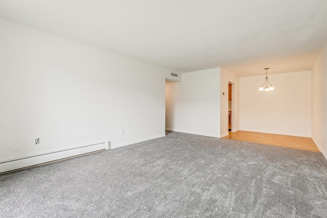 carpeted spare room featuring a baseboard radiator and a notable chandelier