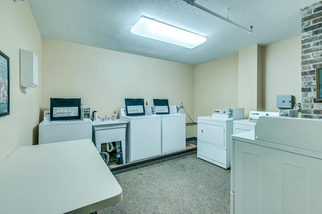 clothes washing area with a textured ceiling, separate washer and dryer, and light carpet